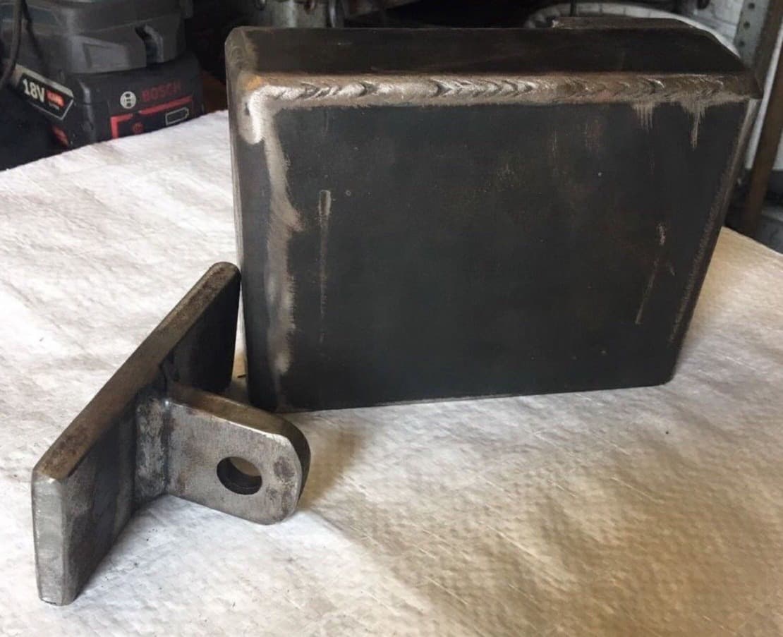 A freshly welded steel lock box with its hinge bracket, ready to be fitted to a container door